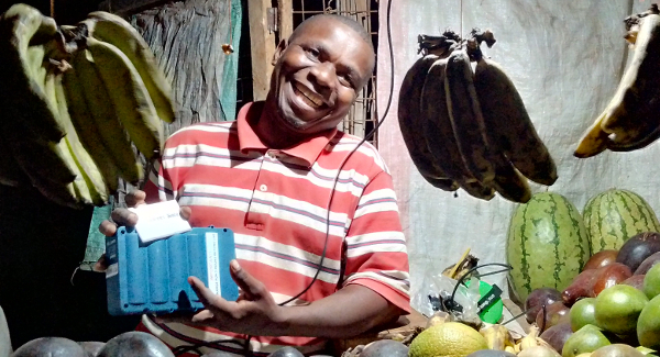 One of SunSweet Solar's customers with a solar kit. He owns a fruit shop in Kibaoni, 5km north-west of Ifakara.
